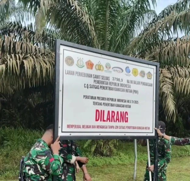Personel TNI memasang papan larangan di kebun sawit terkait Perpres No. 5 Tahun 2025. (Foto/Istimewa)